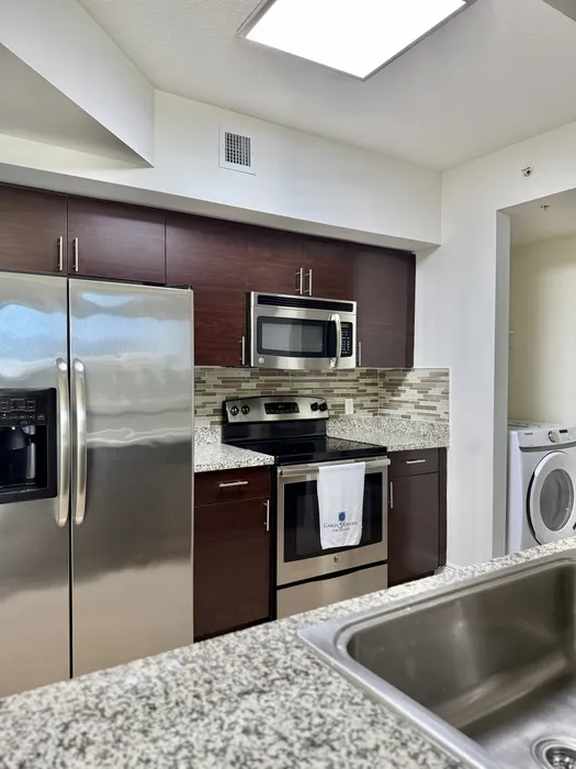 Modern kitchen with sleek stainless steel appliances, granite countertops, and elegant dark wood cabinets, exuding contemporary charm.