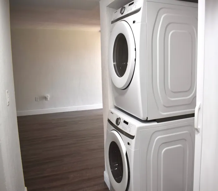 Modern apartment features a convenient in-unit stacked washer and dryer, with elegant hardwood flooring.