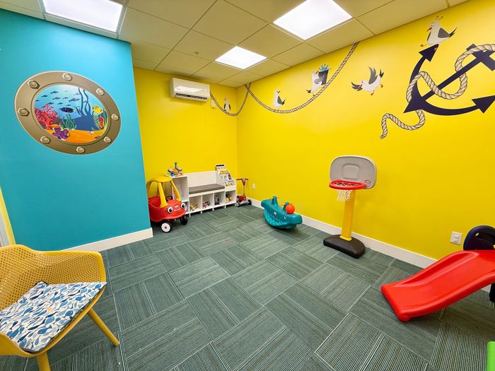 Vibrant children's playroom with colorful wall art, slide, toy car, and a mini basketball hoop.