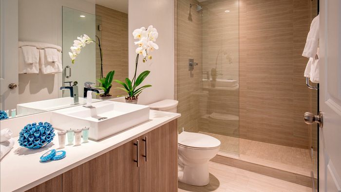 Elegant bathroom with modern fixtures, spacious walk-in shower, and stylish storage solutions, accented by fresh orchids.