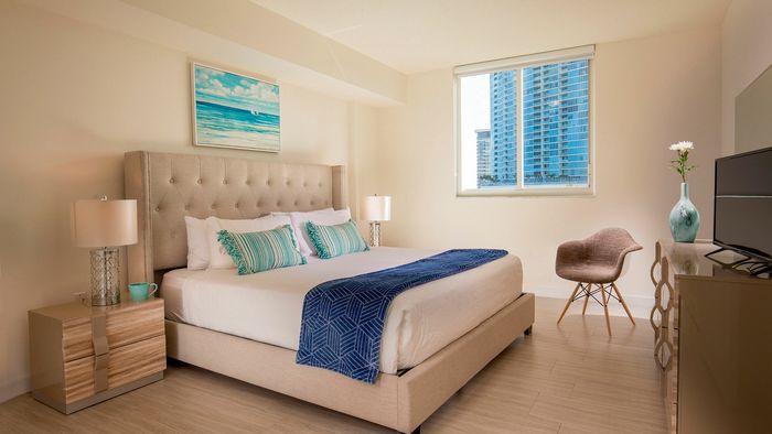 Bright and modern bedroom with elegant decor, featuring a plush bed, stylish bedside tables, and a scenic city view.