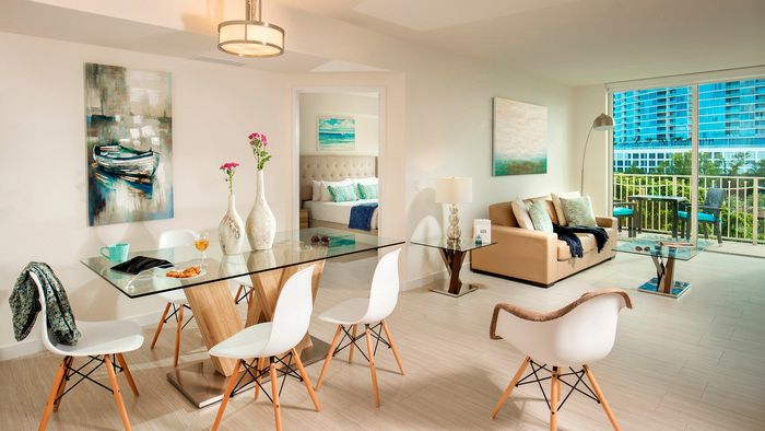Bright, modern living space featuring elegant dining area, cozy sofa, and large windows offering stunning cityscape views.