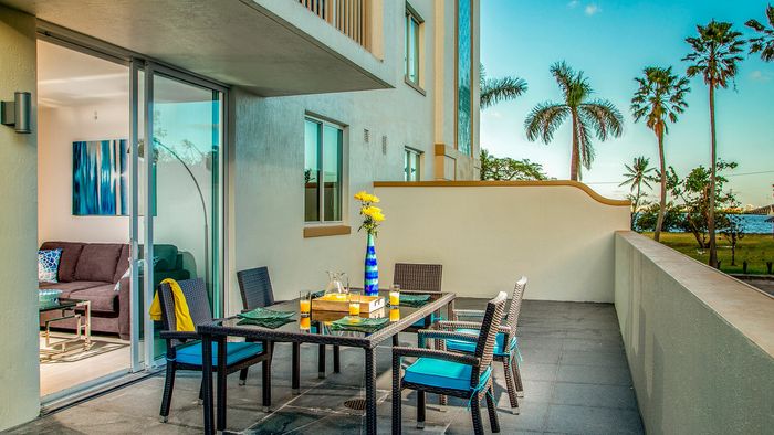 Chic patio with elegant outdoor dining set, vibrant blue decor, and beautiful ocean views, perfect for relaxing.