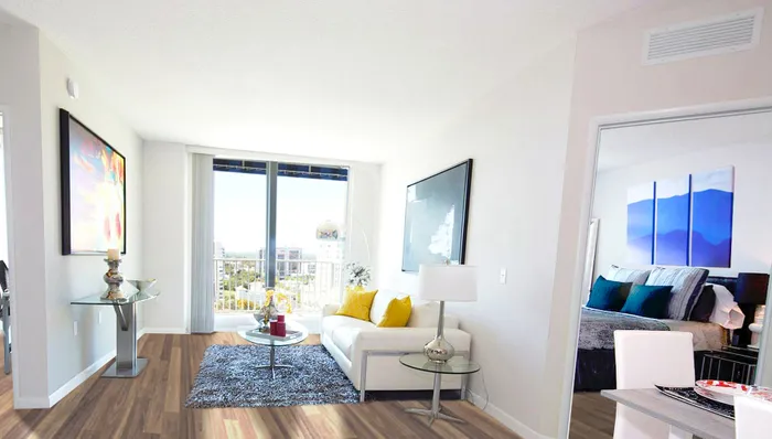 Bright and modern apartment living room with elegant decor, featuring a cozy sofa, vibrant artwork, and a scenic balcony view.