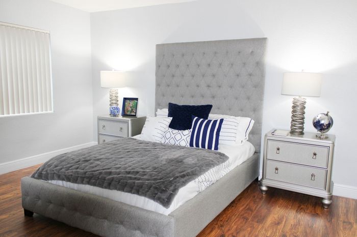 Elegant bedroom with plush gray headboard, stylish bedding, and chic side tables accentuated by modern lamps.