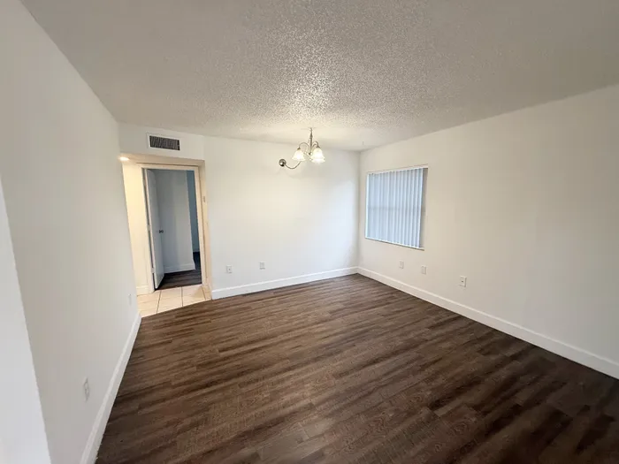 Bright, airy room with elegant wood flooring and modern lighting, perfect for a cozy living space.