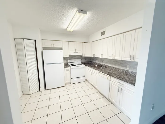 Bright and spacious kitchen with sleek white cabinetry, modern appliances, and elegant granite countertops.