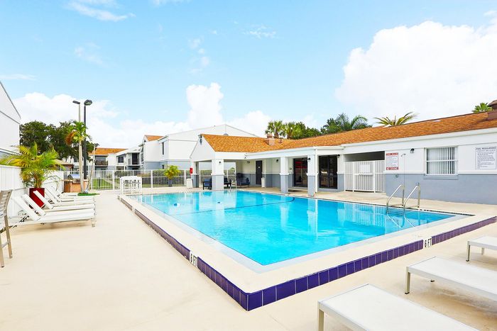 Inviting pool area in a modern apartment complex with comfortable lounge chairs and tropical landscaping, perfect for relaxation and leisure.