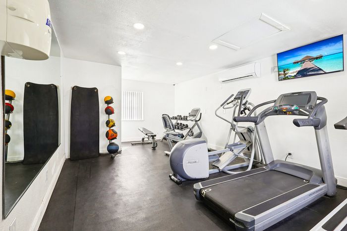 Modern fitness room with state-of-the-art treadmills, exercise bike, free weights, and large mirrors, designed for an invigorating workout experience.