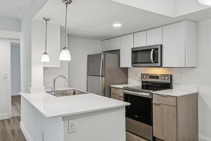 Modern kitchen with sleek stainless steel appliances, elegant pendant lighting, and a chic white countertop.