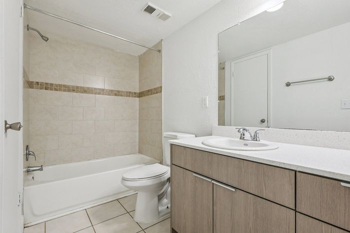 Modern bathroom with elegant tile design, sleek vanity, and spacious mirror for an elevated living experience.