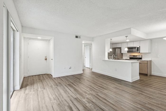 Modern open-concept living space with stylish hardwood floors, bright kitchen with stainless steel appliances, ideal for a chic and welcoming home.