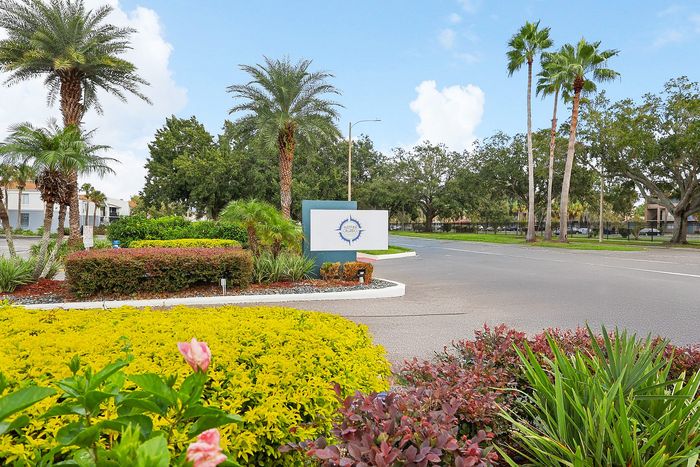Inviting entrance with vibrant landscaping and palm trees, welcoming you to a lush, green community setting.