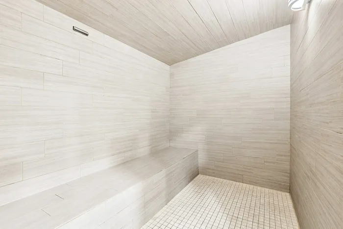 Elegant sauna room with sleek tiled walls and a cozy seating area.
