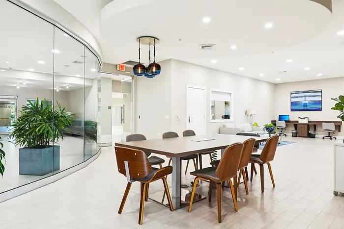 Modern apartment lobby with elegant wooden furniture, cozy seating area, and vibrant potted plants, perfect for relaxation and social gatherings.