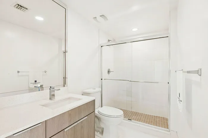 Sleek and modern bathroom with a spacious glass shower, elegant vanity, and bright ambient lighting.