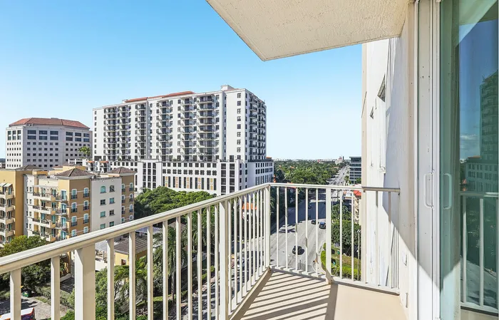 Chic urban balcony offering stunning views of modern high-rise buildings and lush green streets.