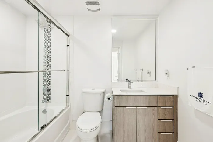 Bright and modern bathroom featuring a sleek glass shower, spacious vanity with ample storage, and elegant tile accents.