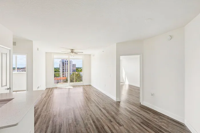 Bright and airy modern apartment with sleek wood flooring, featuring expansive city views from a spacious living area and large windows.