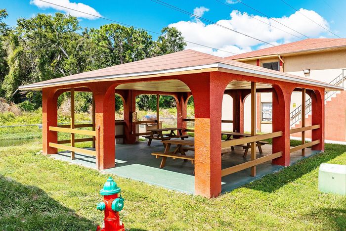 Charming outdoor pavilion with picnic tables nestled among lush greenery, perfect for gatherings and relaxation.