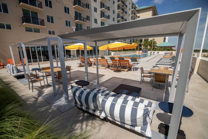 Luxurious apartment rooftop with stylish seating, vibrant umbrellas, and a sparkling pool under a clear blue sky.