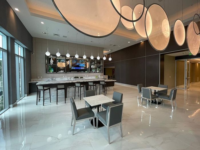 Elegant dining area with modern pendant lighting, sleek marble floors, and a stylish bar with high stools.