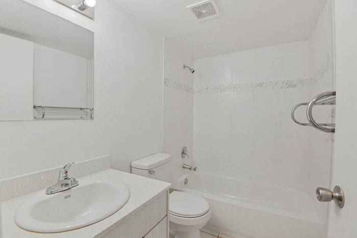 Bright, modern bathroom with elegant tiled shower, sleek white vanity, and minimalist design.