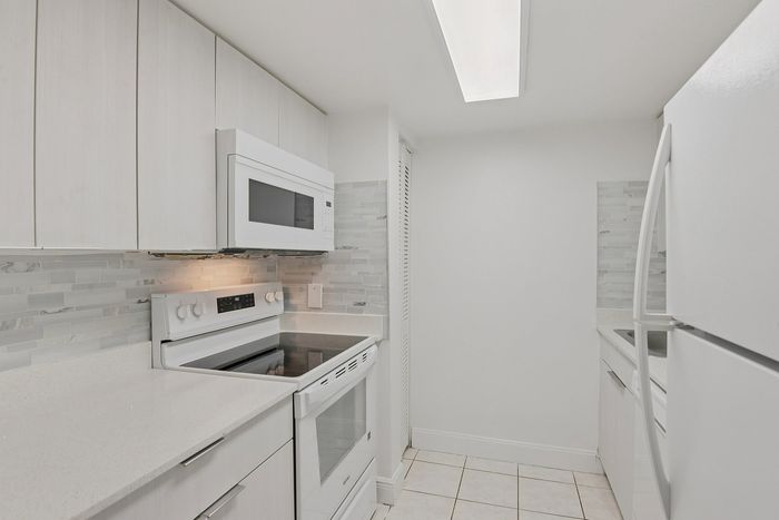 Modern kitchen with sleek white cabinetry, quartz countertops, and stainless steel appliances, perfect for culinary enthusiasts.