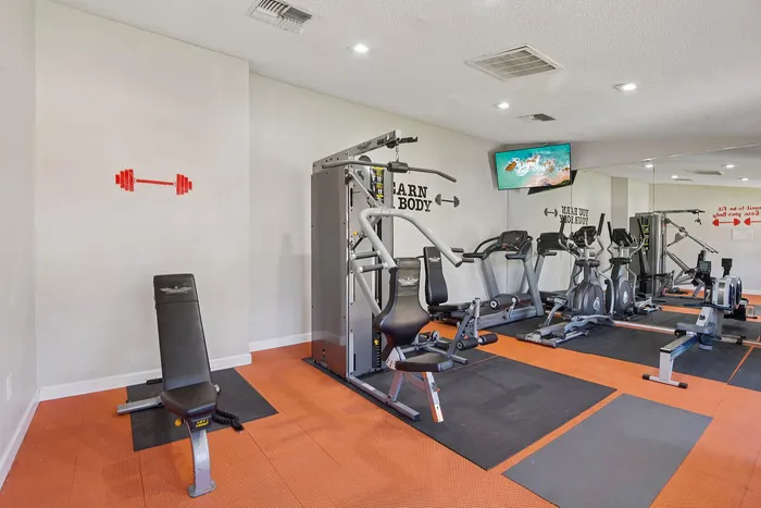 Modern apartment gym equipped with state-of-the-art cardio machines, weight bench, and motivational decor.