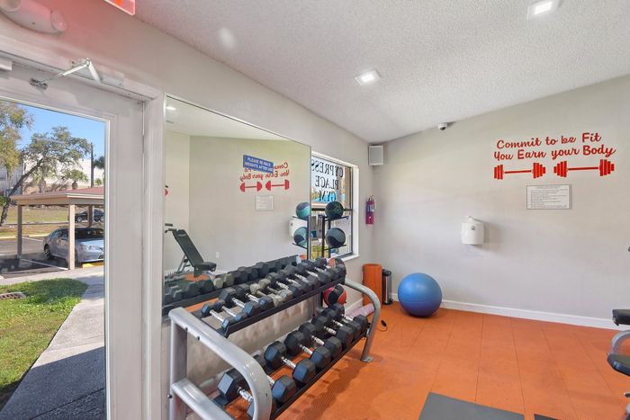 Inviting fitness room with natural light, featuring a range of weights, fitness equipment, and motivational decor.
