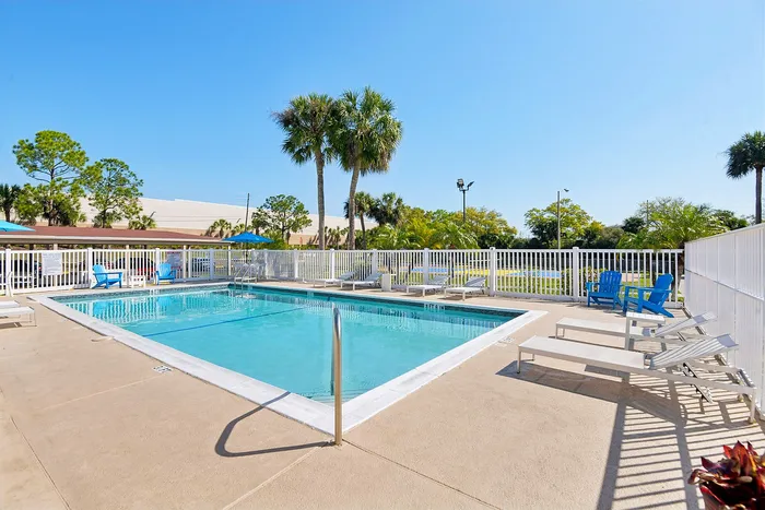 Inviting outdoor pool area with sun loungers, palm trees, and blue skies perfect for relaxation.