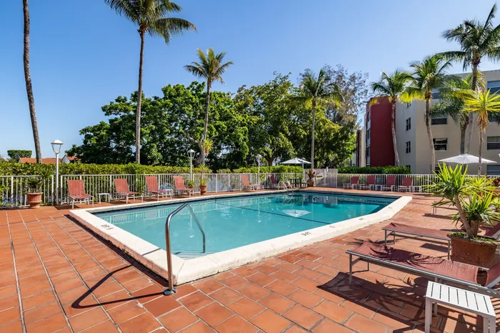 Inviting outdoor pool area with lush greenery and relaxing sun loungers, perfect for a sunny retreat.