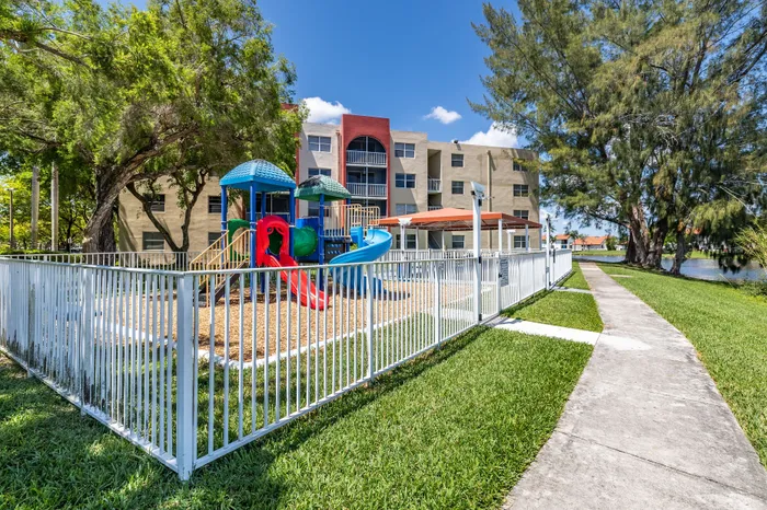 Charming apartment complex with a vibrant playground nestled in lush greenery, perfect for family-friendly living.