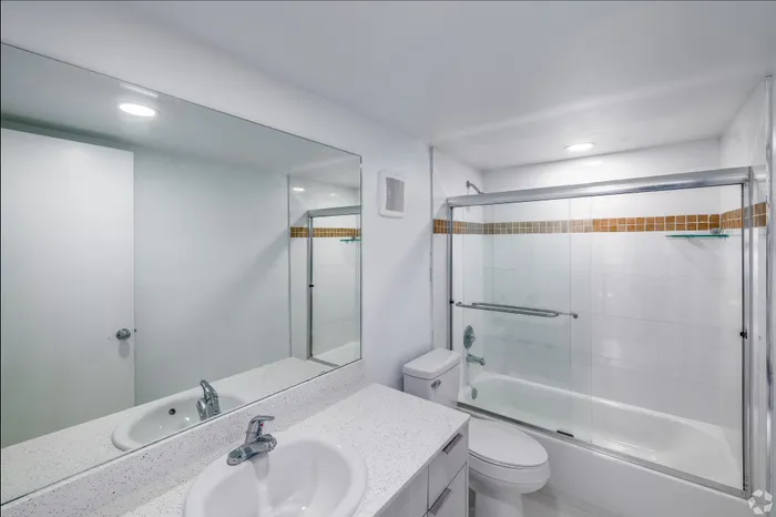 Modern bathroom featuring sleek white fixtures, a spacious glass-enclosed shower, and elegant lighting.