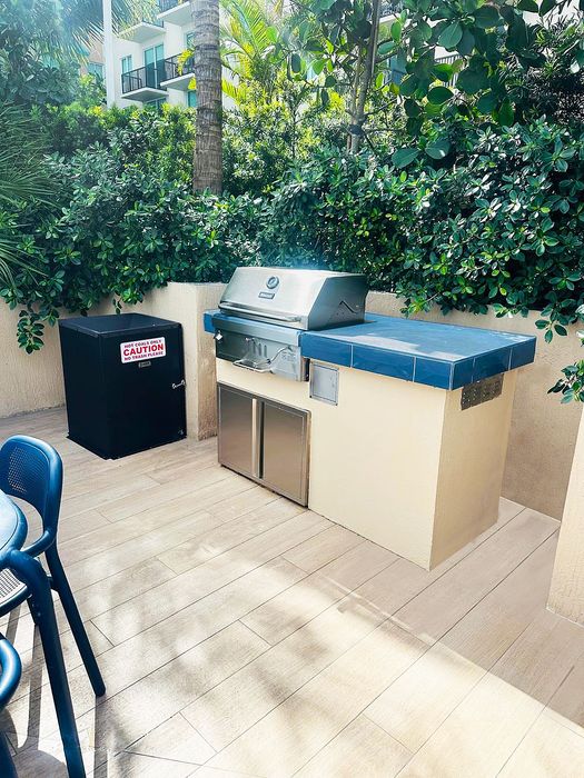 Chic outdoor patio with modern grill and sleek dining area surrounded by lush greenery.