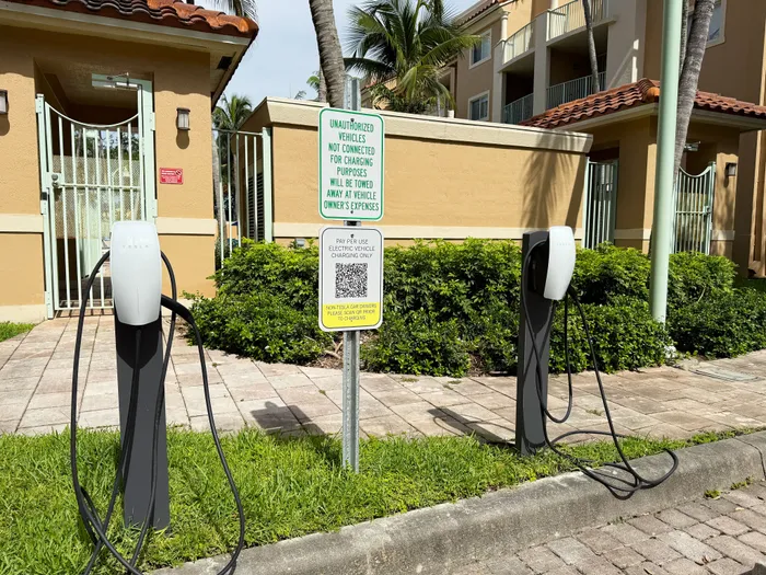 Modern apartment complex featuring convenient electric vehicle charging stations, lush greenery, and gated entrances.