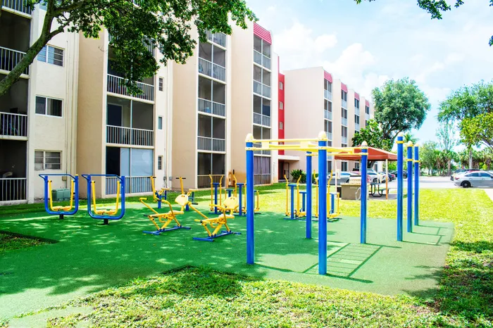 Charming apartment complex featuring a vibrant outdoor fitness area and lush green spaces, perfect for active living.