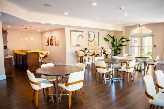 Bright and inviting community room featuring modern seating, elegant wooden furnishings, and stylish decor with ambient lighting.