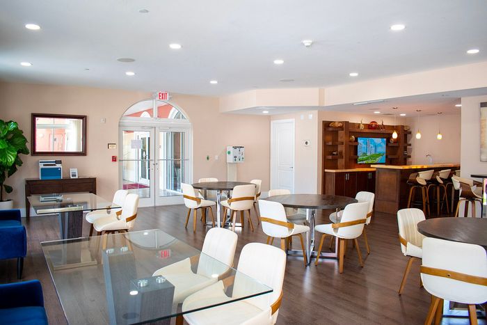 Elegant communal space with modern seating, glass tables, and a stylish bar area, perfect for social gatherings and relaxation.