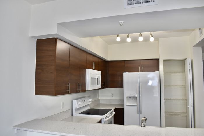 Elegant modern kitchen with sleek wooden cabinets, stainless steel appliances, and a pristine quartz countertop.