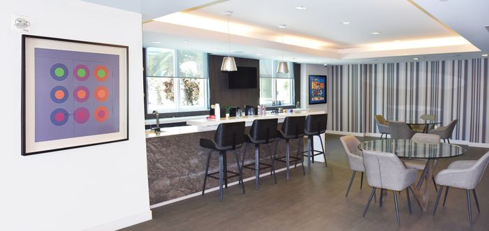 Modern and vibrant communal space featuring a sleek kitchen bar, stylish pendant lighting, and cozy seating area with elegant decor.