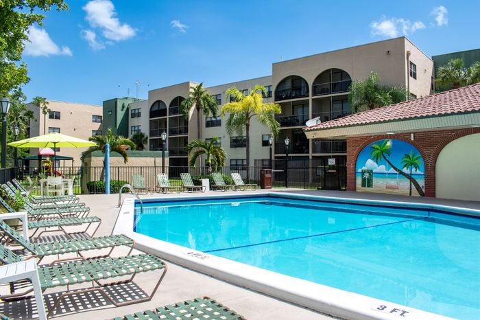 Inviting poolside retreat with modern loungers, vibrant umbrella, and stylish apartment backdrop, perfect for relaxation and entertaining.