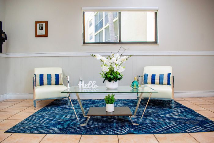 Elegant living room with modern armchairs, a stylish glass coffee table, and vibrant blue accents, offering a welcoming atmosphere.