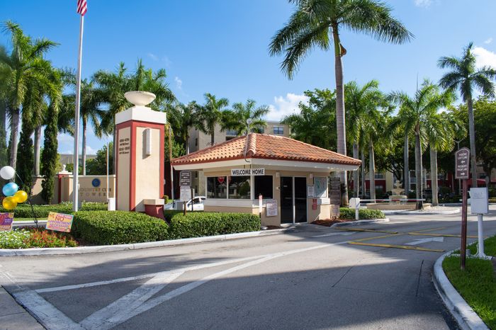 Inviting entrance of a gated community with lush palm trees and welcoming signage.