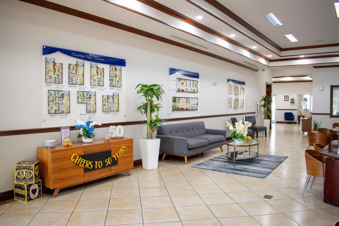 Elegant apartment lobby showcasing floor plans for Country Club Towers, featuring stylish seating, vibrant decor celebrating 50 years, and a welcoming, spacious environment.