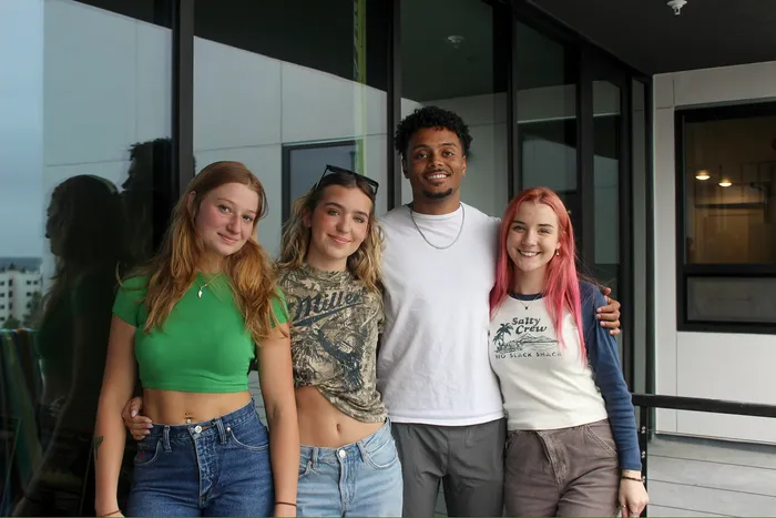 4 people smiling and posing on the balcony.