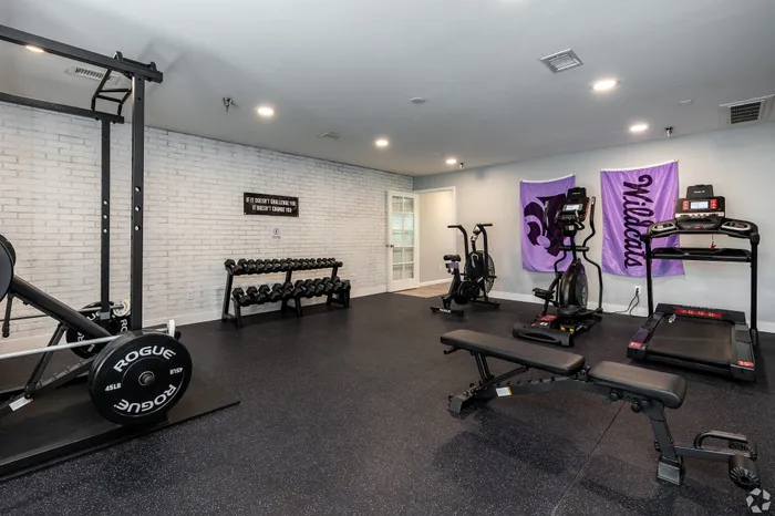 On-site apartment fitness center with free weights, strength training equipment, treadmills, and cardio machines in a clean, well-lit workout space designed for residents&rsquo; daily fitness routines.