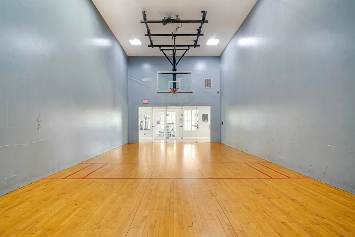 Spacious indoor basketball court with polished hardwood floors and bright overhead lighting, perfect for recreational activities.