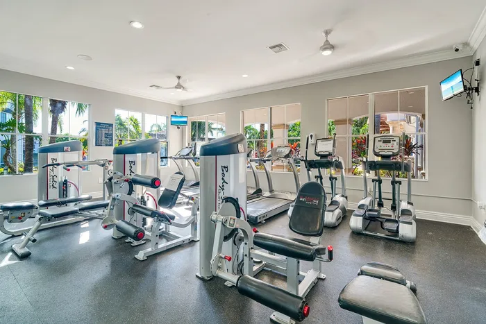 Bright and inviting fitness center equipped with modern exercise machines, large windows, and lush outdoor views.
