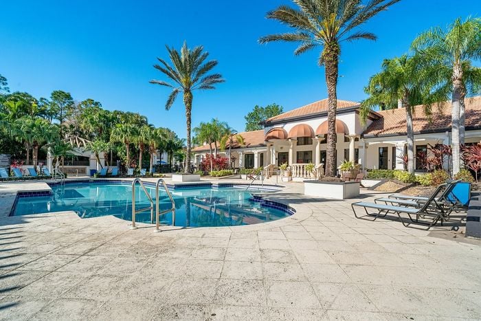 Luxurious apartment complex with a sparkling pool, surrounded by palm trees and elegant architecture, perfect for relaxation and enjoyment.